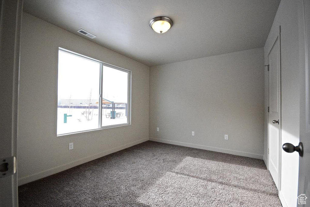 Carpeted empty room featuring baseboards and visible vents