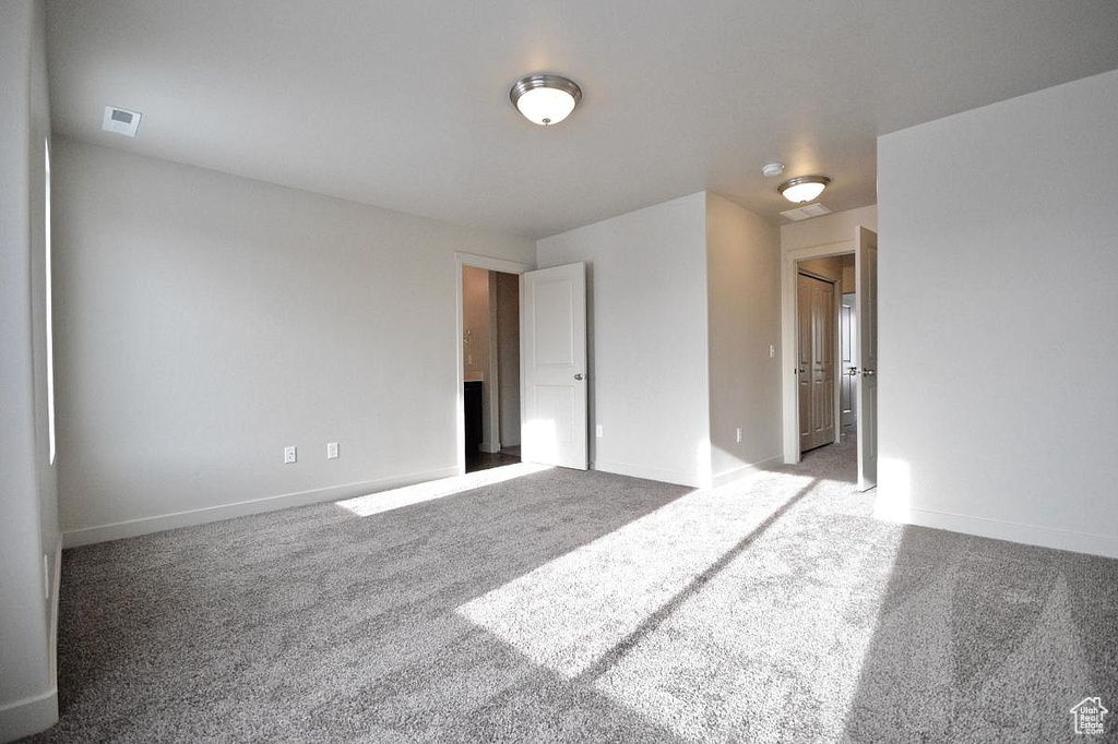 Carpeted empty room with baseboards and visible vents