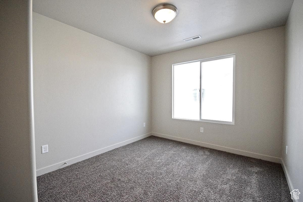 Empty room with baseboards, visible vents, and carpet flooring
