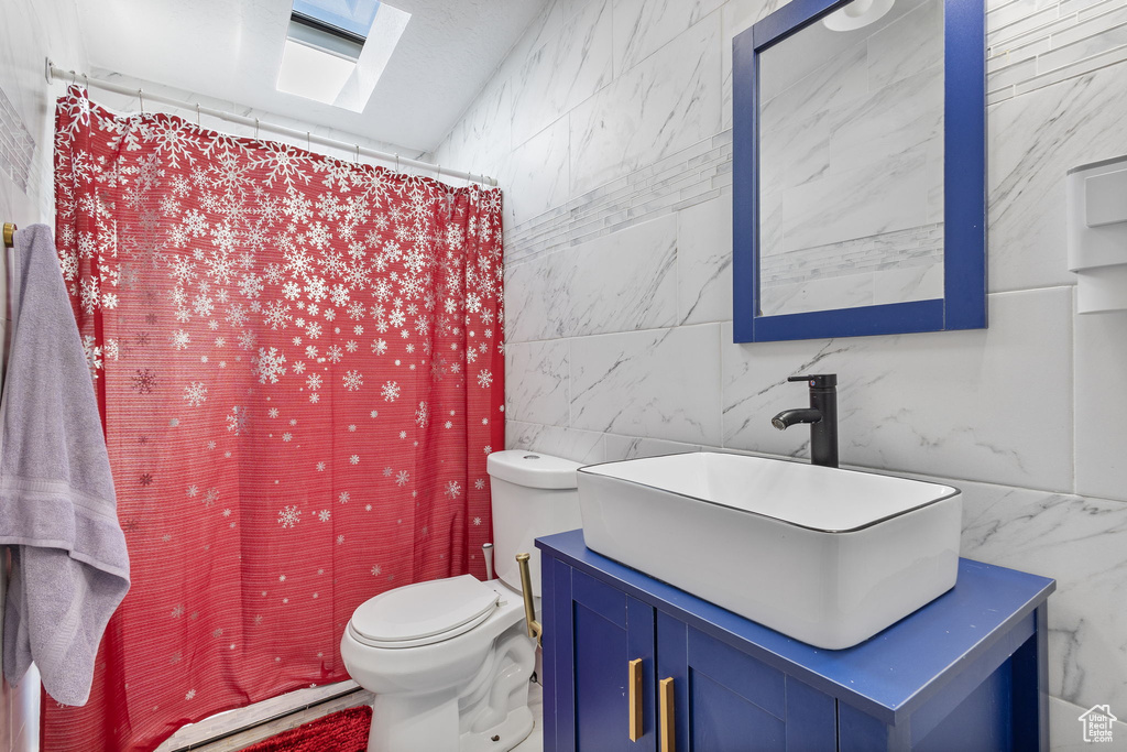 Full bath featuring tile walls, curtained shower, vanity, toilet, and marble finish floor