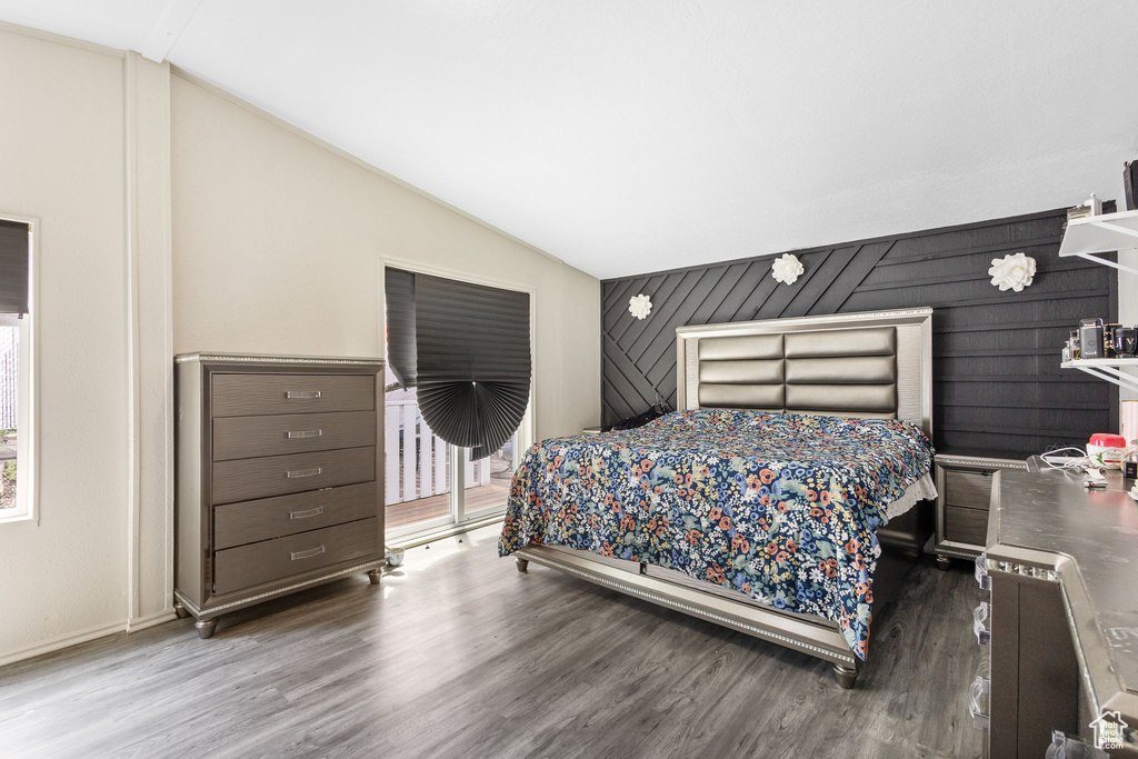 Bedroom featuring wood finished floors, lofted ceiling, and access to outside