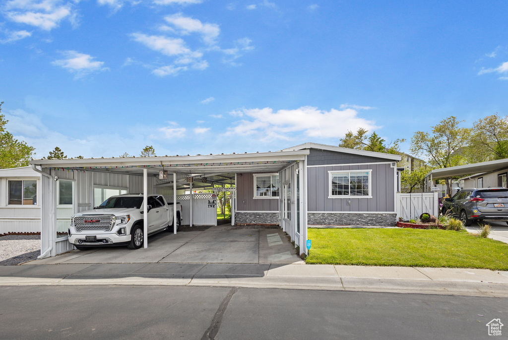 Manufactured / mobile home featuring fence, an attached carport, and a front lawn