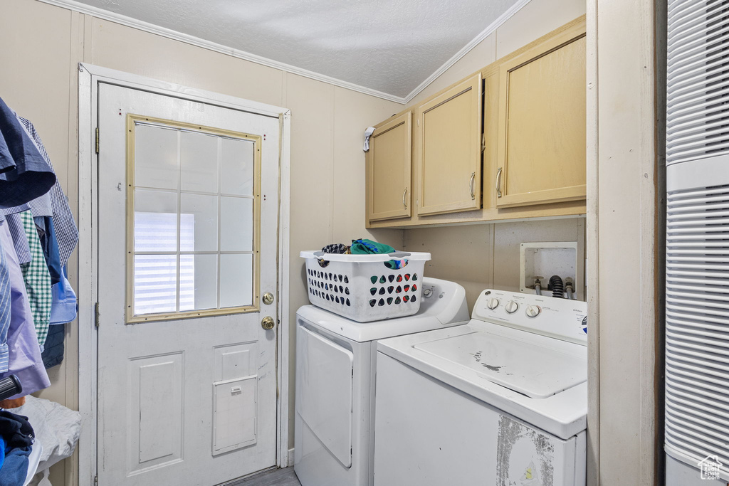 Laundry area featuring ornamental molding, cabinet space, a heating unit, and washer and clothes dryer