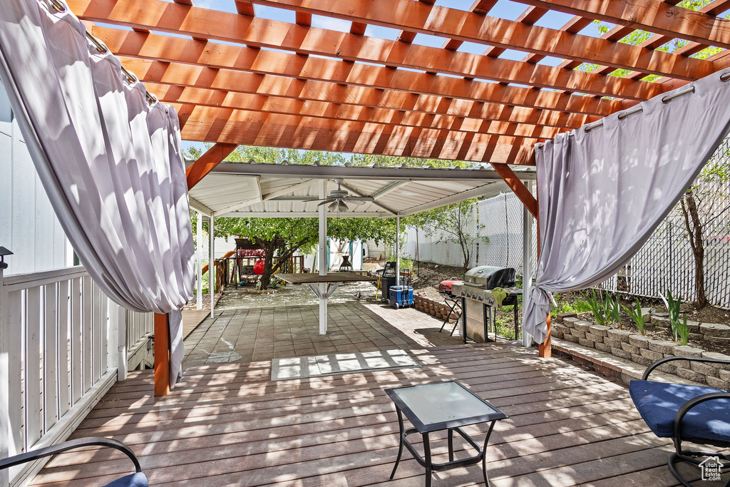 Deck featuring a fenced backyard, a ceiling fan, a pergola, and grilling area