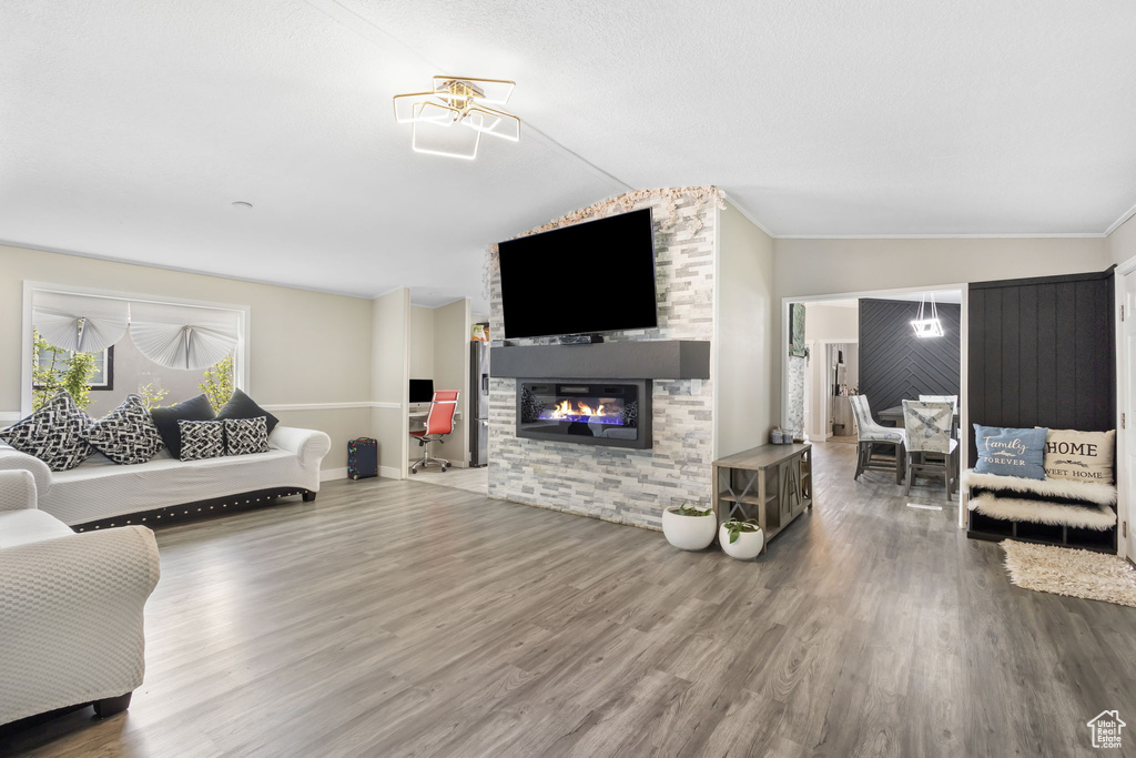 Living room with crown molding, wood finished floors, lofted ceiling, and a fireplace