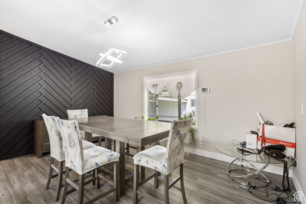 Dining area with baseboards, a chandelier, ornamental molding, and wood finished floors