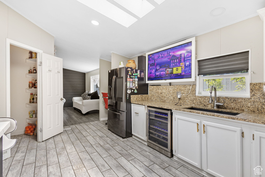 Kitchen with wine cooler, stainless steel fridge with ice dispenser, a sink, light wood-style flooring, and backsplash