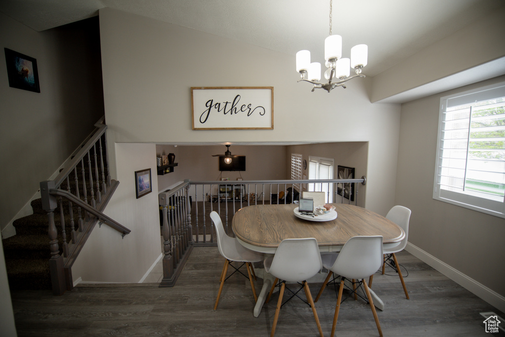 Dining room featuring baseboards, an inviting chandelier, wood finished floors, and lofted ceiling
