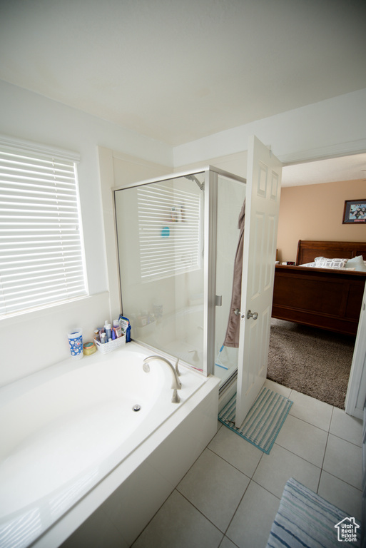 Full bath with tile patterned flooring, a bath, and a stall shower