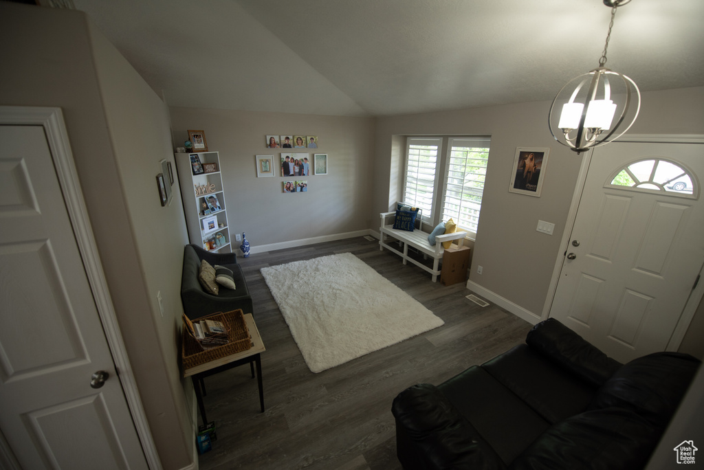 Foyer with an inviting chandelier, vaulted ceiling, dark wood-style flooring, and a healthy amount of sunlight
