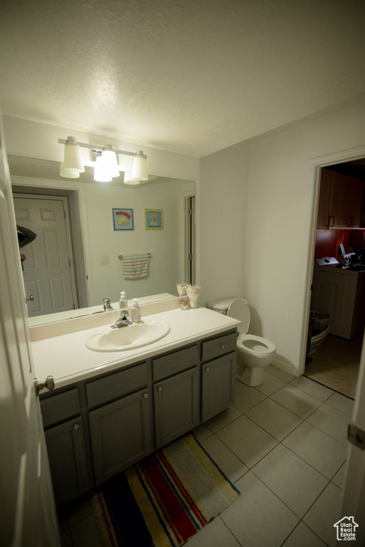 Bathroom with vanity, tile patterned flooring, toilet, and a textured ceiling