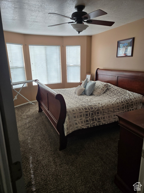 Carpeted bedroom featuring baseboards, a ceiling fan, and a textured ceiling