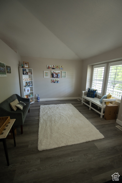 Living room with baseboards, vaulted ceiling, and dark wood finished floors
