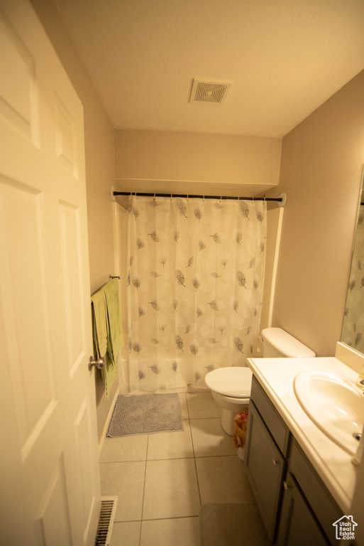 Full bathroom featuring toilet, tile patterned floors, visible vents, and vanity