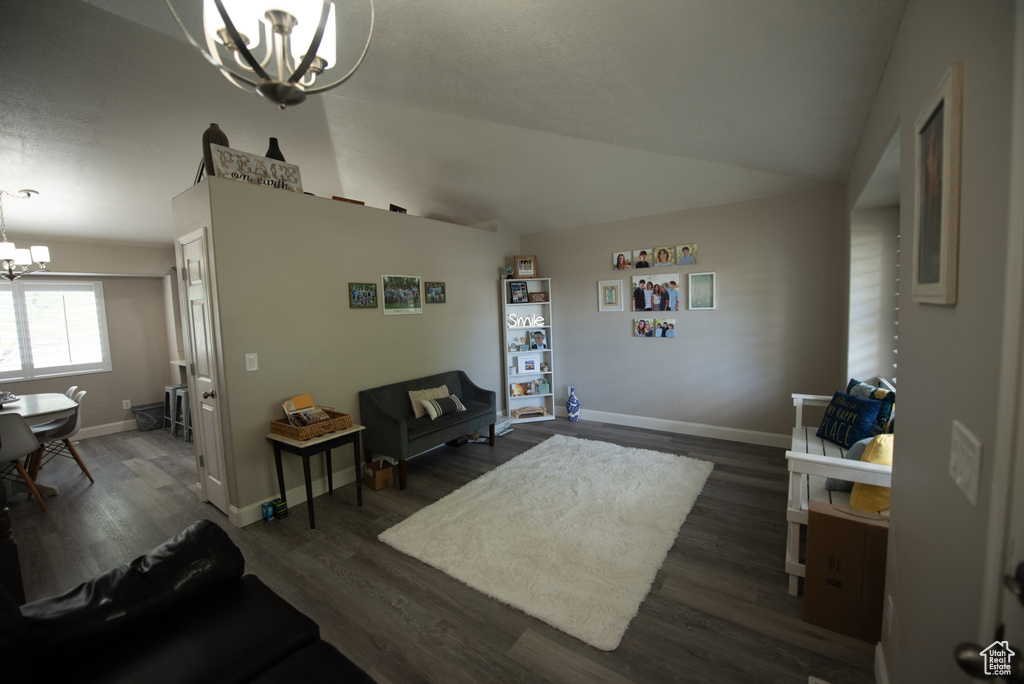 Interior space featuring baseboards, an inviting chandelier, dark wood-style floors, and lofted ceiling