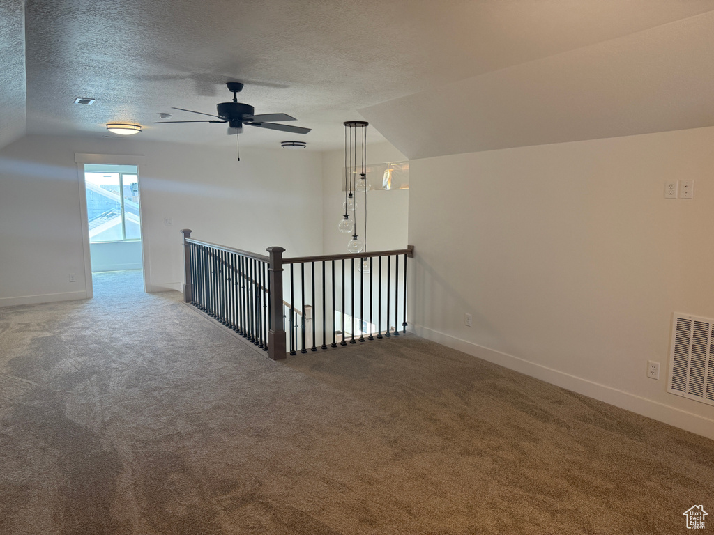 Carpeted empty room with lofted ceiling, a textured ceiling, and ceiling fan