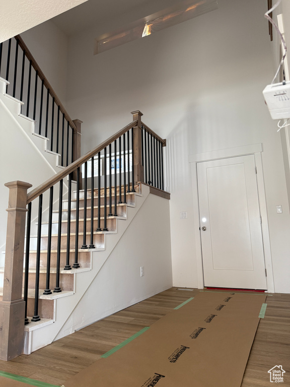 Entryway with wood finished floors, a high ceiling, and stairs