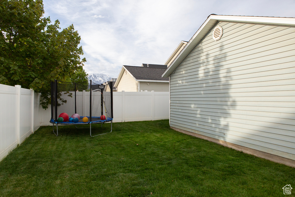View of yard featuring a trampoline and a fenced backyard