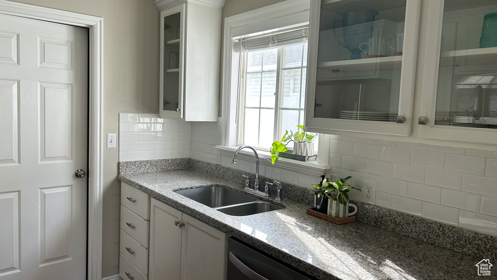 Kitchen featuring glass insert cabinets, a sink, white cabinets, and tasteful backsplash