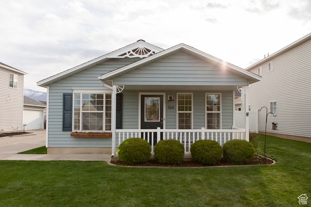Bungalow-style home featuring an outbuilding, a front lawn, and covered porch