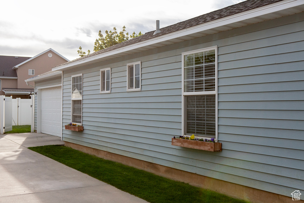 View of home's exterior with concrete driveway, an attached garage, and fence