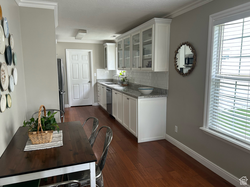 Kitchen featuring decorative backsplash, stainless steel appliances, a wealth of natural light, white cabinets, and a sink