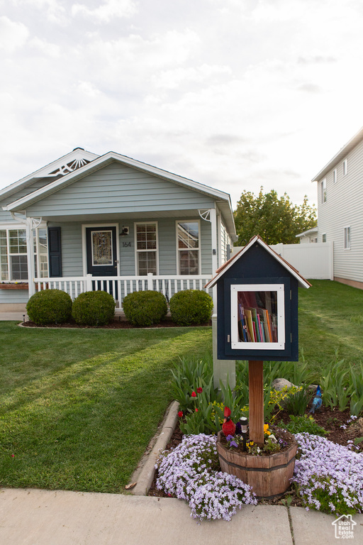 View of front of property featuring fence, covered porch, and a front yard