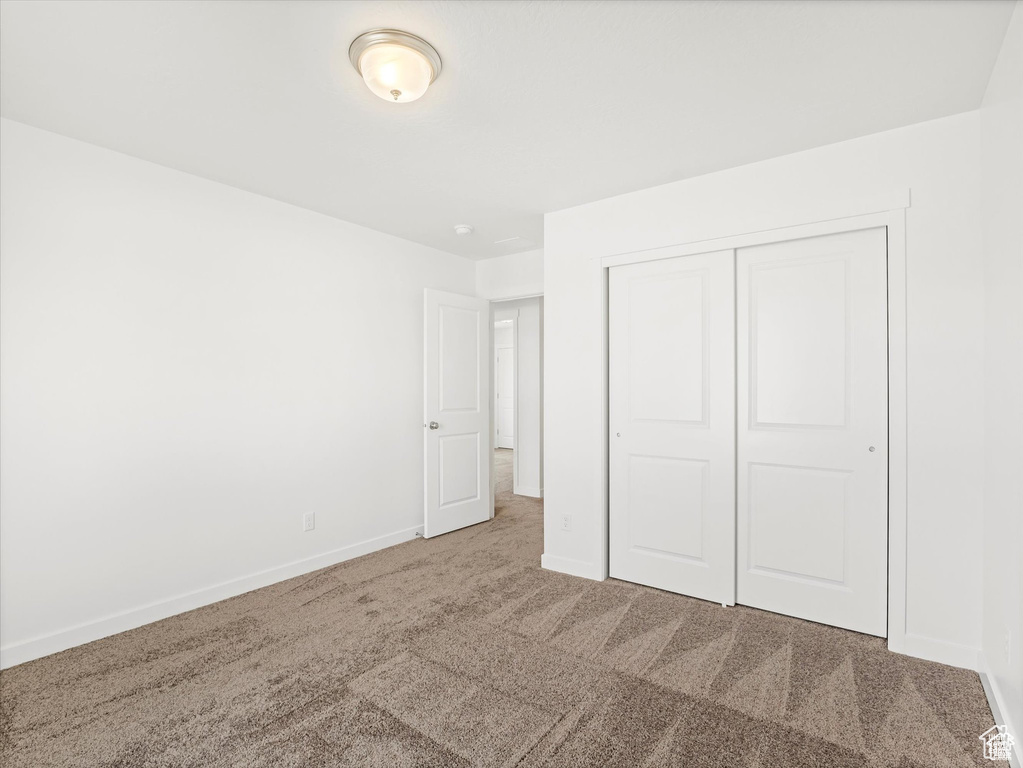 Unfurnished bedroom with a closet, carpet flooring, and baseboards