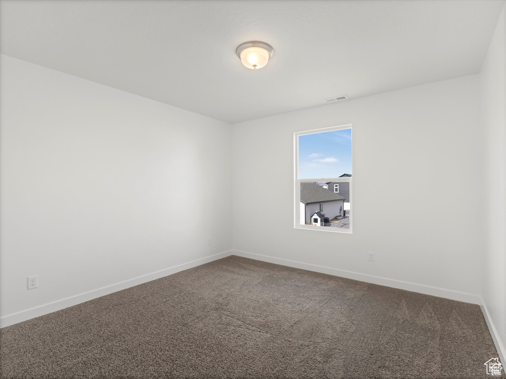 Empty room with visible vents, carpet flooring, and baseboards