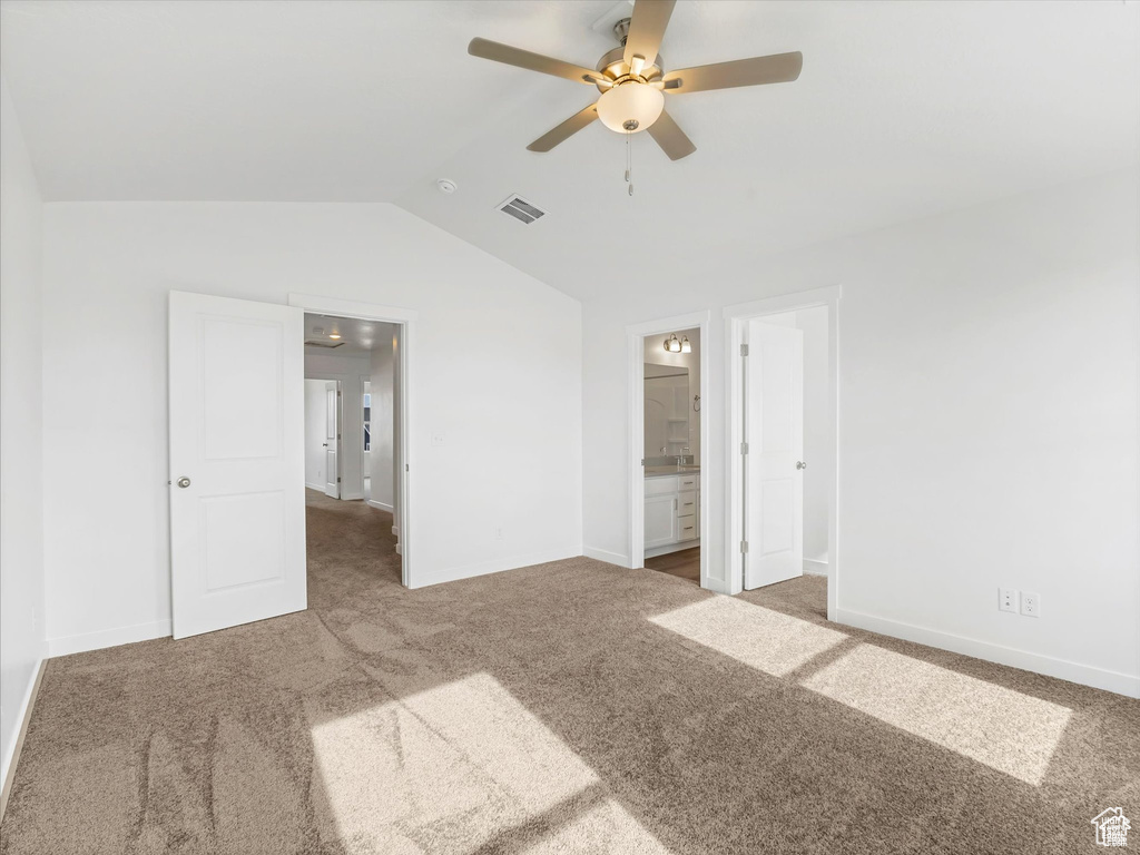 Unfurnished bedroom with lofted ceiling, visible vents, carpet flooring, and baseboards
