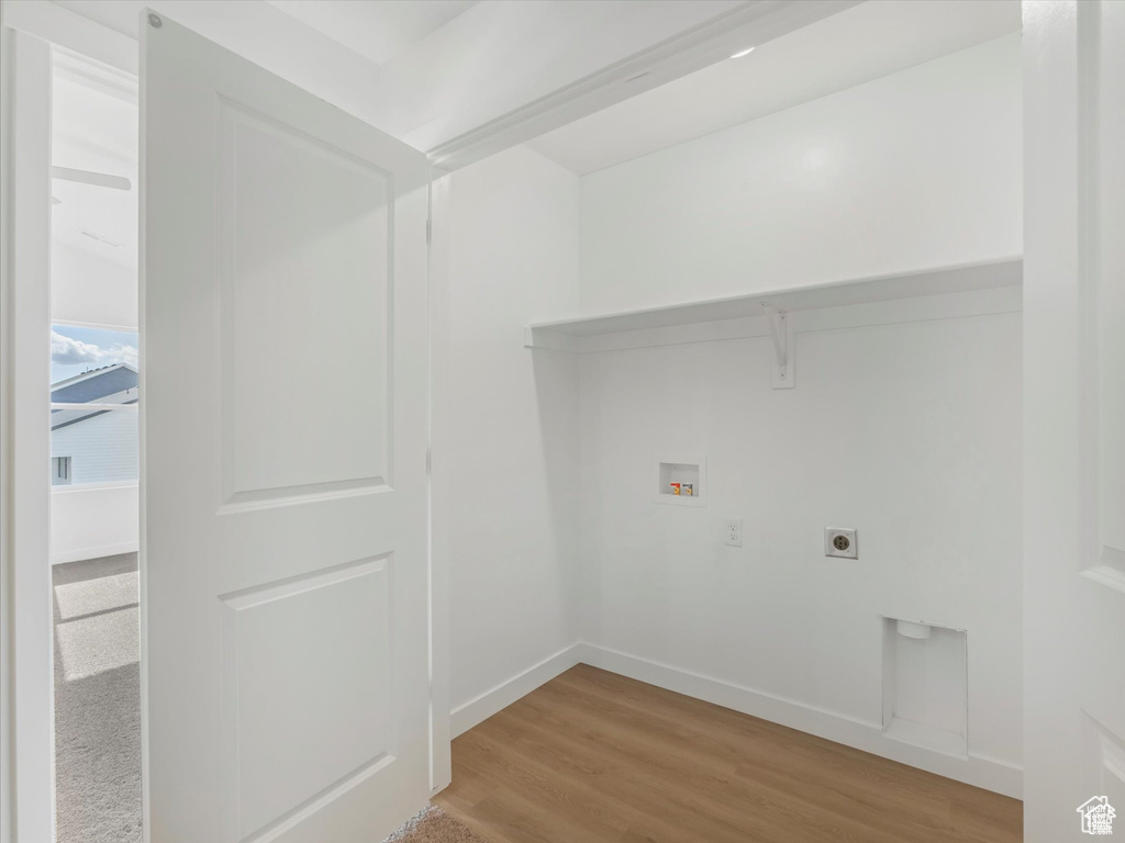 Laundry area with hookup for an electric dryer, washer hookup, baseboards, light wood-type flooring, and laundry area