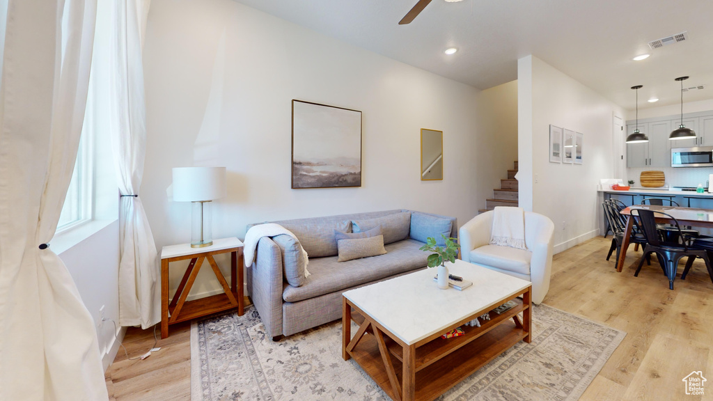 Living area with visible vents, a ceiling fan, baseboards, and light wood-style floors
