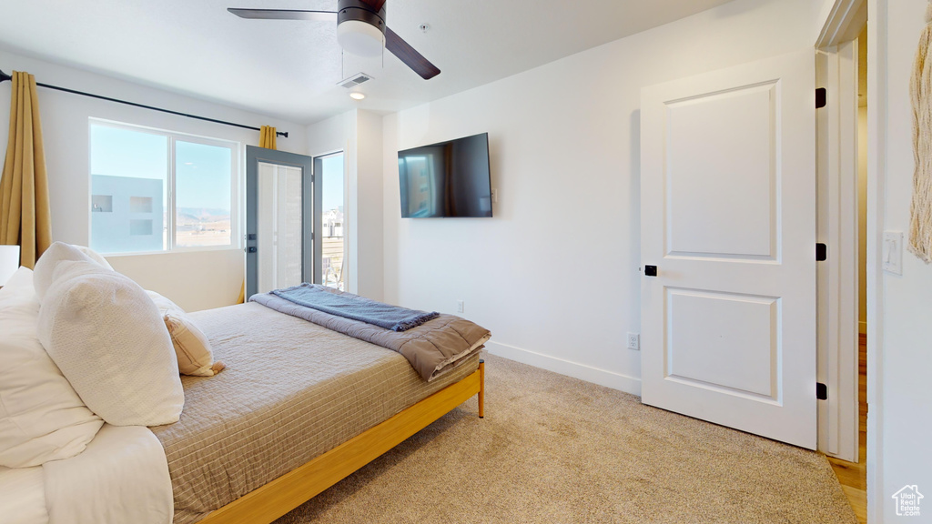 Bedroom featuring light colored carpet, visible vents, a ceiling fan, and baseboards