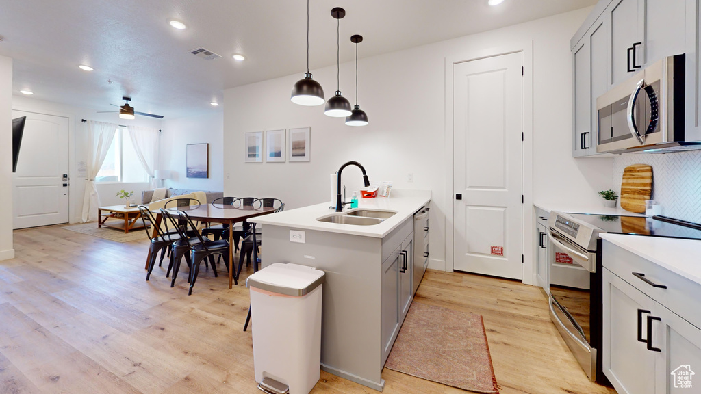 Kitchen featuring a sink, appliances with stainless steel finishes, visible vents, light wood-type flooring, and a peninsula