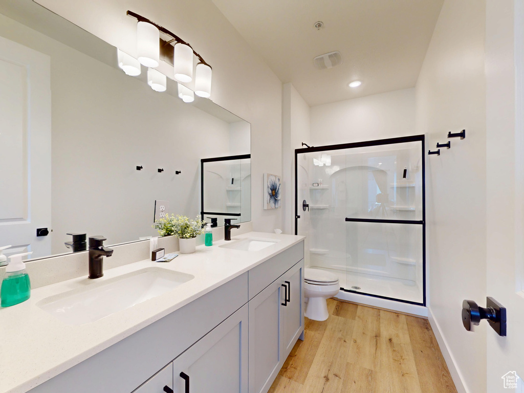 Full bathroom with wood finished floors, a shower stall, toilet, and a sink