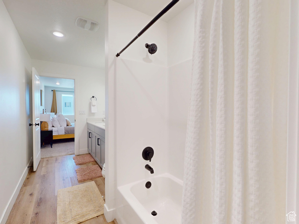 Ensuite bathroom with ensuite bathroom, baseboards, shower / tub combo with curtain, wood finished floors, and vanity