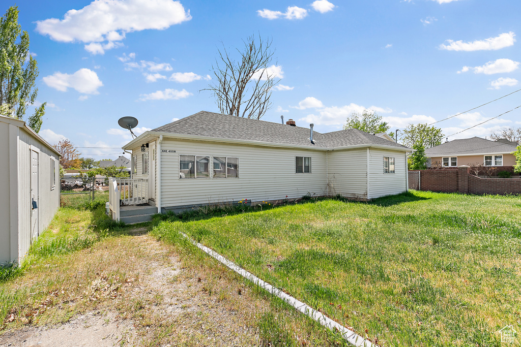 Back of house with fence and a yard
