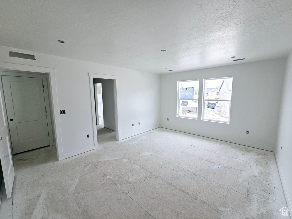 Empty room featuring baseboards and a textured ceiling