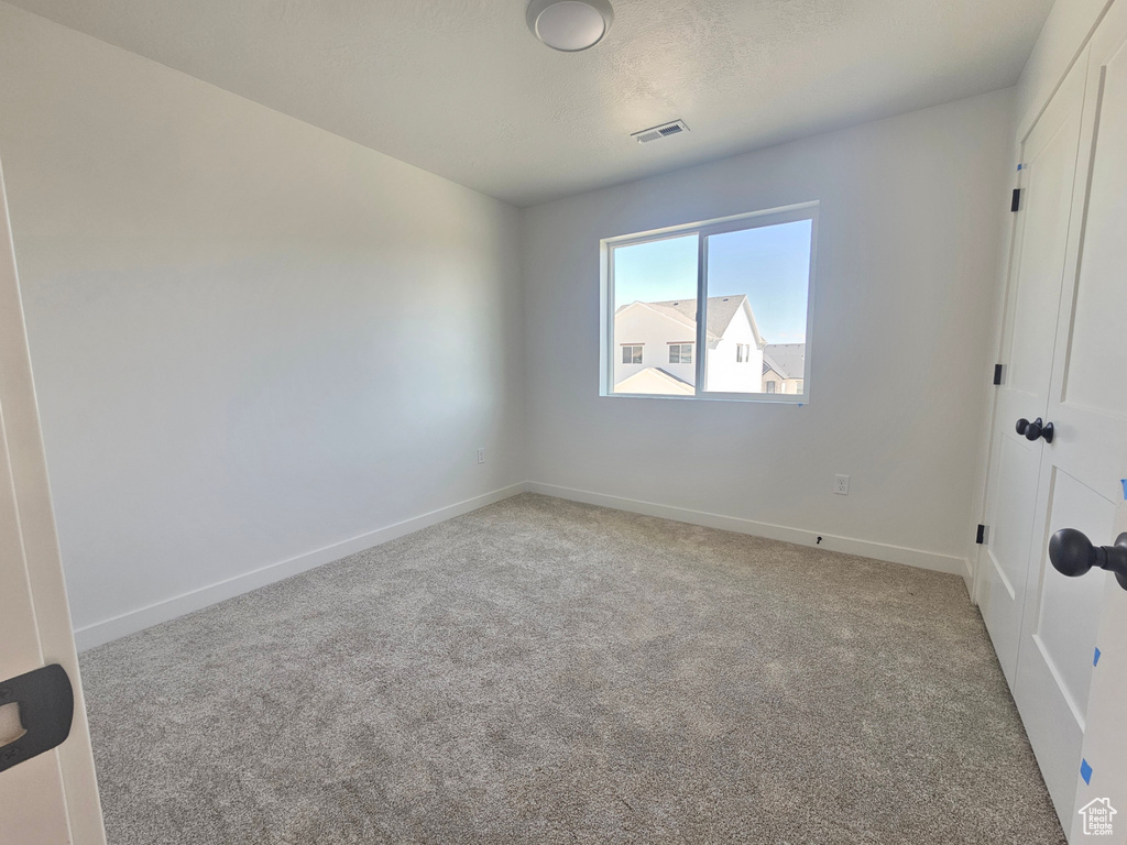 Empty room with light colored carpet and baseboards