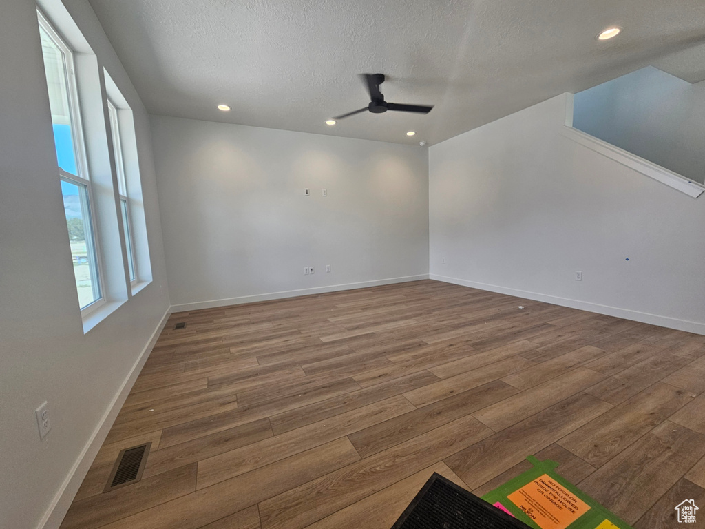 Spare room with wood finished floors, ceiling fan, a textured ceiling, recessed lighting, and baseboards