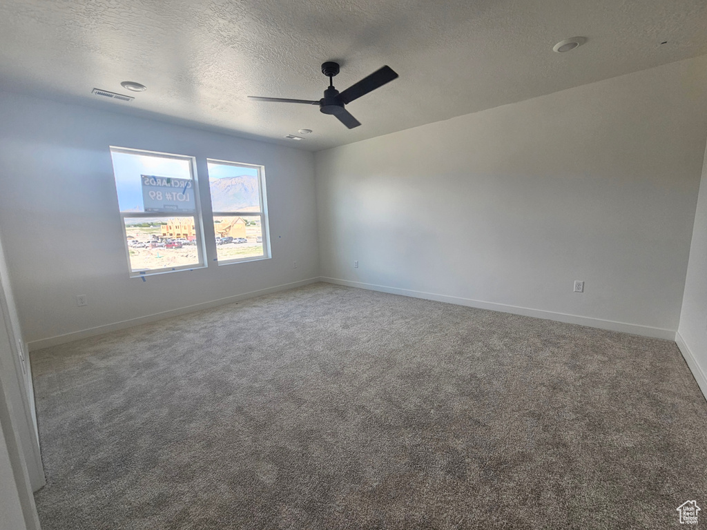 Unfurnished room featuring ceiling fan, a textured ceiling, carpet, and baseboards