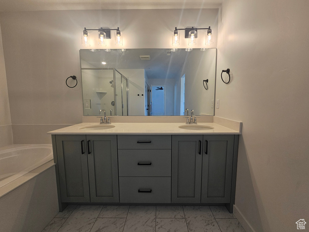 Full bath featuring marble look tiles, a stall shower, double vanity, and a garden tub