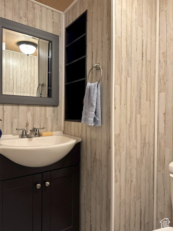 Bathroom with wood walls, toilet, vanity, and built in features