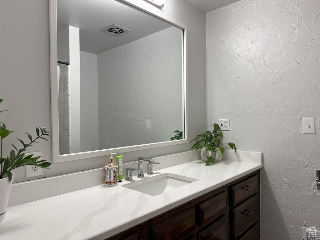 Bathroom featuring visible vents, vanity, and a textured wall