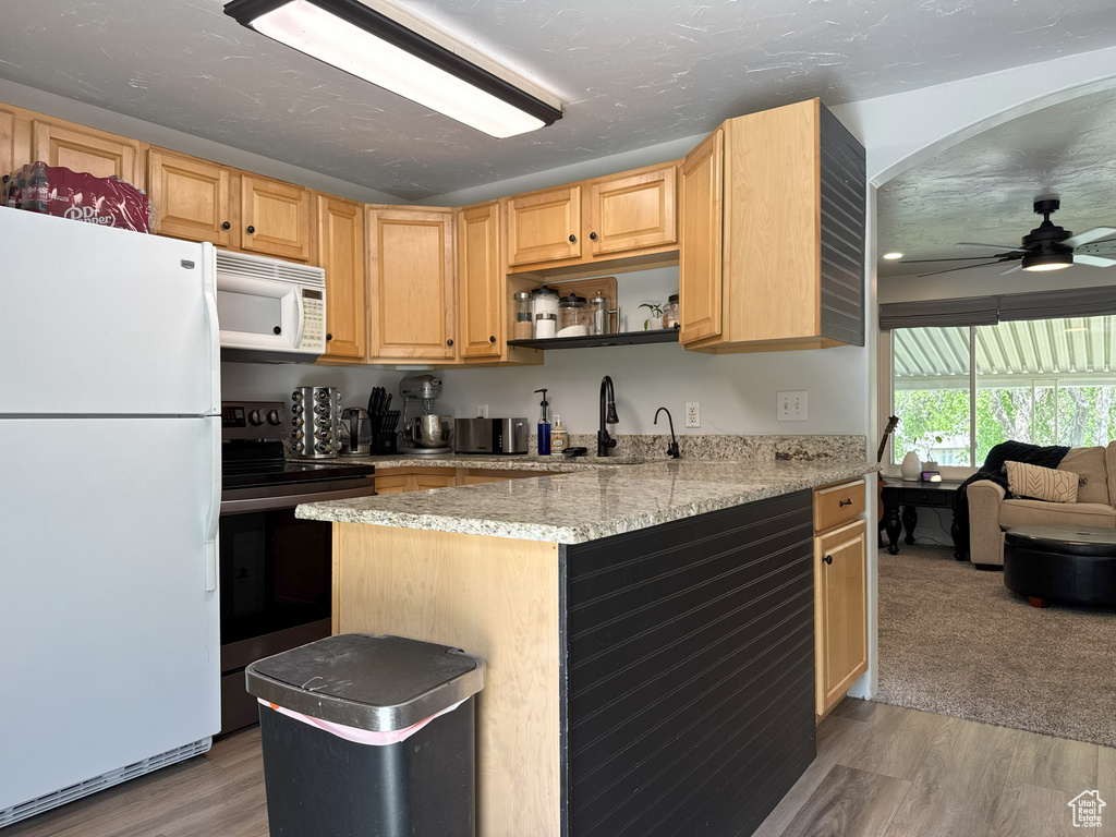 Kitchen featuring white appliances, light wood finished floors, ceiling fan, and a sink