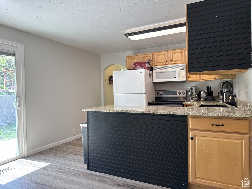 Kitchen with a sink, visible vents, light brown cabinetry, light wood finished floors, and white appliances