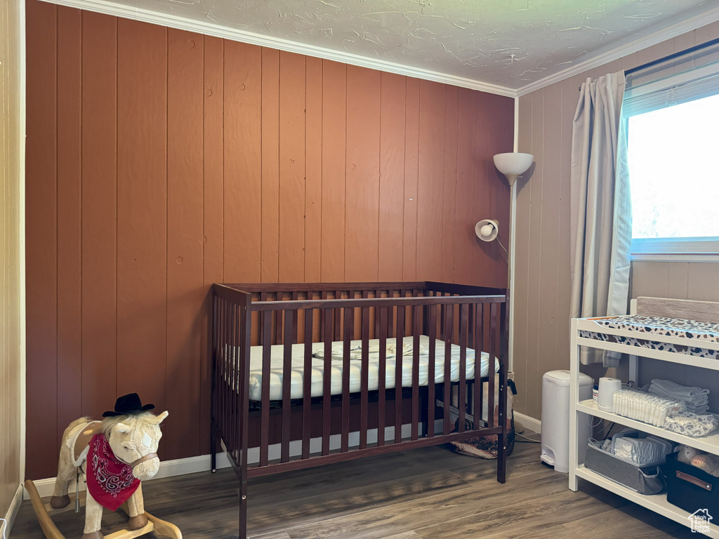 Bedroom with wood finished floors and ornamental molding