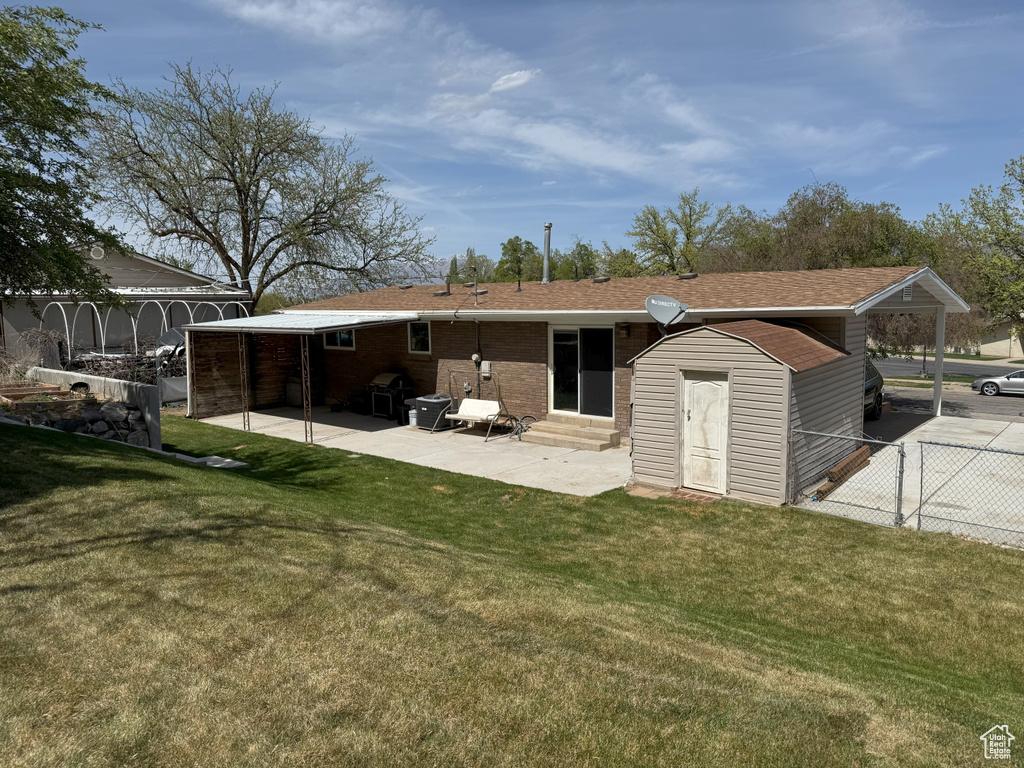Back of property featuring a patio, entry steps, a storage unit, a lawn, and fence