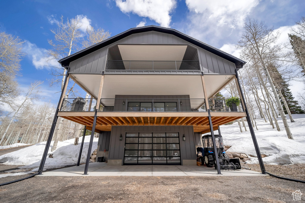View of front of house with board and batten siding, a balcony, and an attached garage