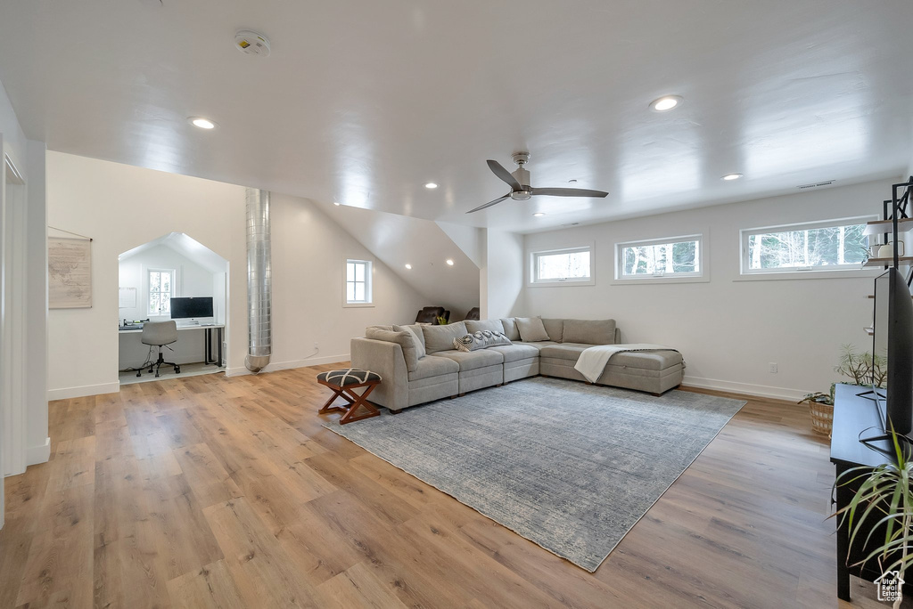Living area featuring ceiling fan, baseboards, light wood finished floors, and arched walkways
